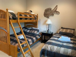 A bunk bed room with a ladder, a bedside table with a lamp, and a wall decoration. - Large home in the Tahoe Keys! (South Lake Tahoe)