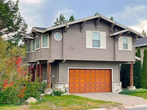A two-story house with a garage, a covered porch, and a landscaped front yard. - Large home in the Tahoe Keys! (South Lake Tahoe)