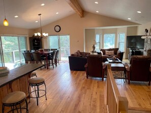 A spacious living area with a dining area, a kitchen, and a large TV. - Large home in the Tahoe Keys! (South Lake Tahoe)