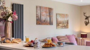 Una cocina con una preparación para el desayuno, incluyendo croissants, un bol de fresas y un vaso de zumo de naranja.