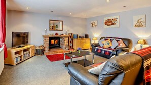 Ein Wohnzimmer mit Kamin, Fernseher, Sofa und Couchtisch.