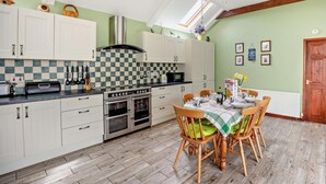 Eine Küche mit weißen Schränken, einer karierten Spritzschutzleiste, einem eingebauten Backofen und einem Essbereich mit Tisch und Stühlen.