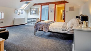 Ein Schlafzimmer mit einem Bett, einem Schminktisch, einem Heizkörper, einem Spiegel und einem Dachfenster.