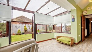 Ein Zimmer mit einer großen Glasdoor, einem Korbsessel und einem Holzboden.