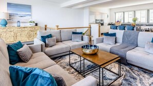 A modern living room with a sofa set, a coffee table, and a kitchen area in the background. - 5 Bed in Bideford (oc-80650) (Westward Ho!)