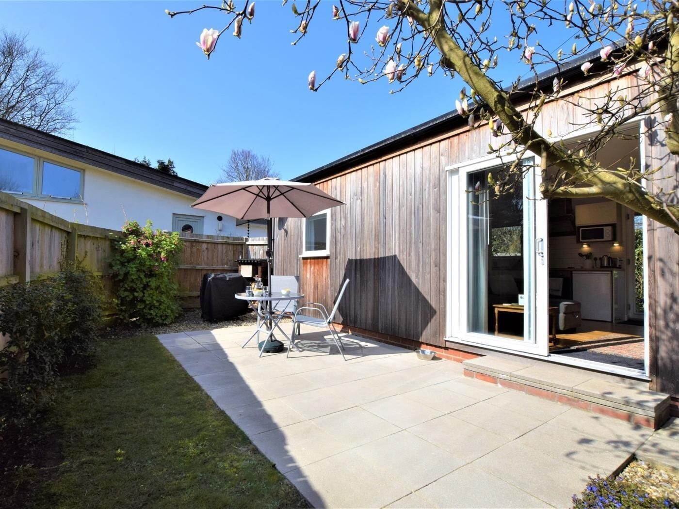 A backyard with a patio, a grill, and a sliding glass door leading to a kitchen.