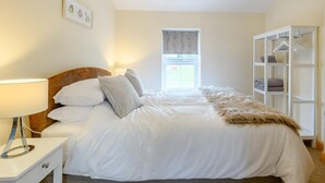 Ein Schlafzimmer mit Bett, Nachttisch, Lampe, Kleiderschrank und Deckenleuchte.