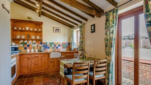Una cocina rústica con armarios de madera, un salpicadero de azulejos y un comedor con mesa y sillas.
