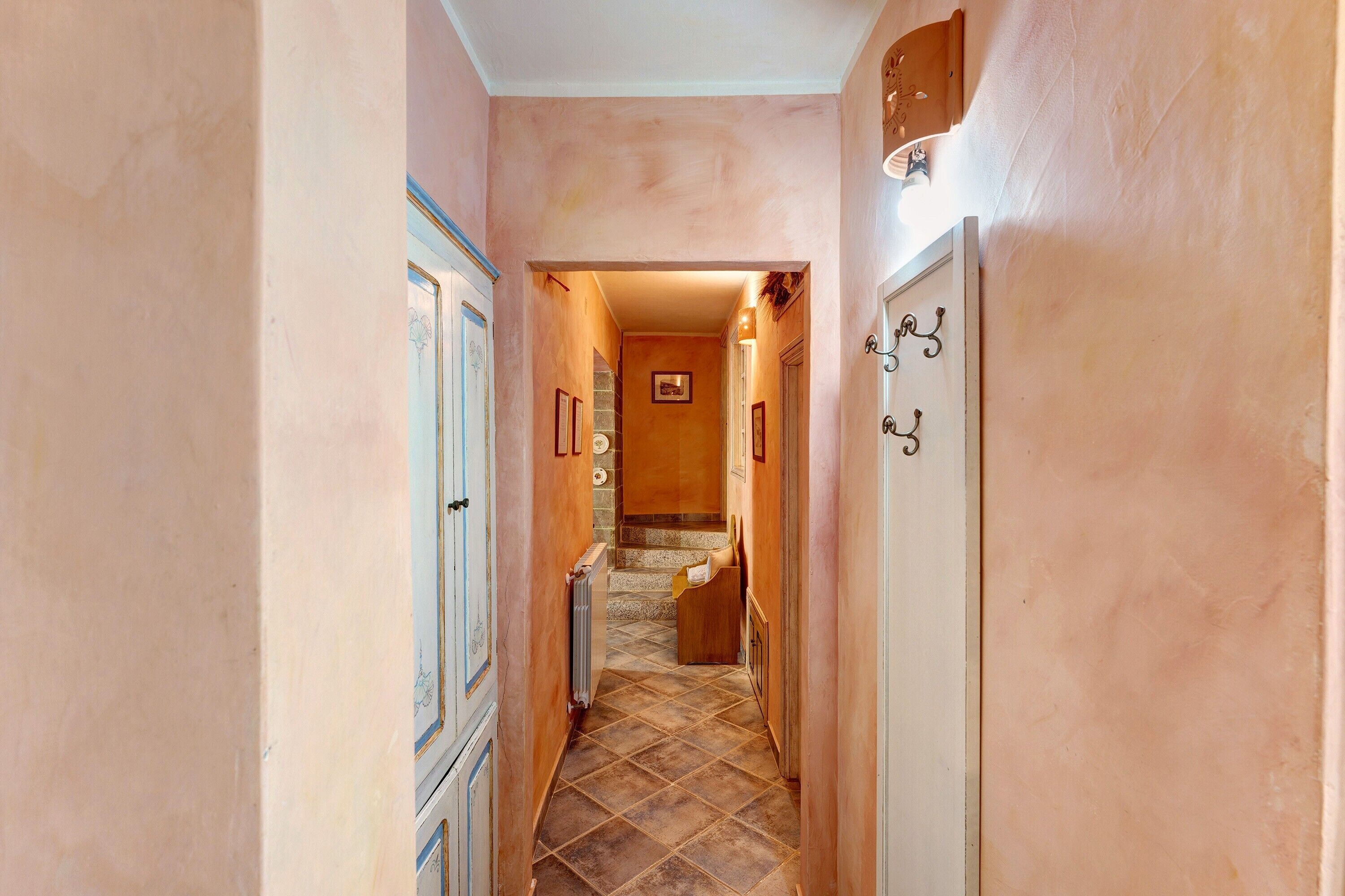 A narrow hallway with a tiled floor, leading to a staircase.