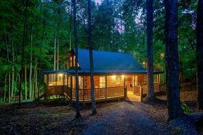 A cabin with a porch, surrounded by trees. - Cedar Cabin Stay (Sevierville)