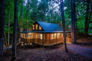 A cabin with a wooden exterior, a porch, and a staircase leading to the entrance. - Cedar Cabin Stay (Sevierville)