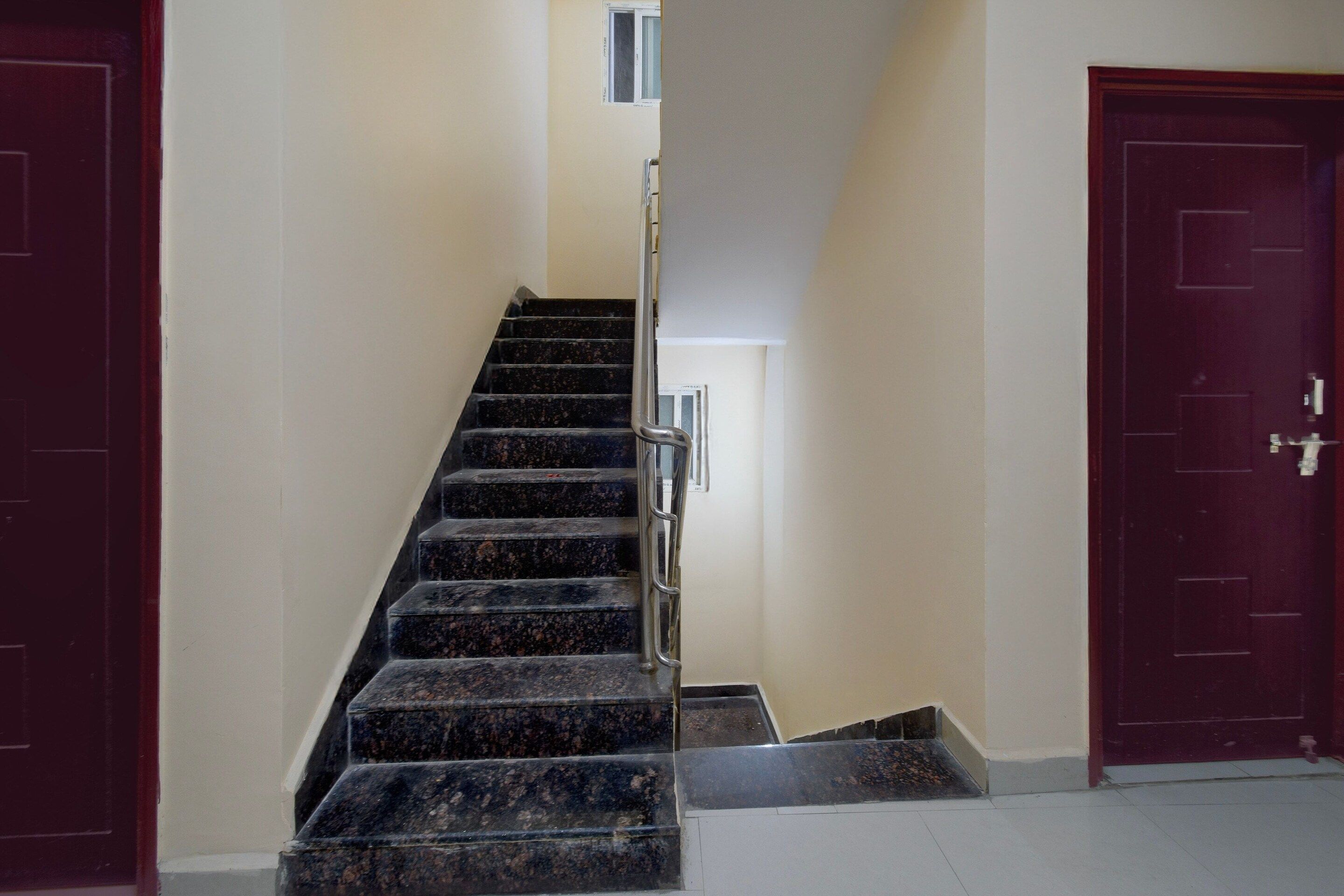 A staircase with a handrail leading to a landing, flanked by two doors on either side.
