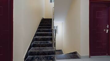 A staircase with a handrail leading to a landing, flanked by two doors on either side.