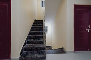 A staircase with a handrail leading to a landing, flanked by two doors on either side. - Classic Hotel O SLN Gachibowli (Hyderabad)