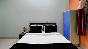 A room with a bed, a nightstand, a blue wardrobe, and a wall with a curtain.