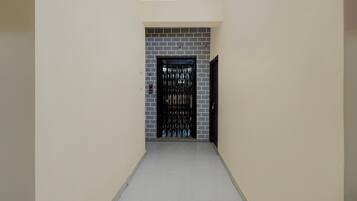 A corridor with a door at the end, a tiled floor, and a wall with a brick pattern.