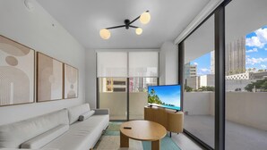 A modern living room with a sofa, a coffee table, a TV, and a balcony with a city view. - WorldCenter Miami Luxury 2 BR - Pool (Miami)