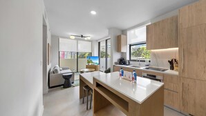 A modern kitchen with wooden cabinets, a white countertop, and a dining area with a sofa and a coffee table. - WorldCenter Miami Luxury 2 BR - Pool (Miami)