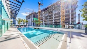 A swimming pool with a modern design, surrounded by a building under construction with scaffolding and cranes. - WorldCenter Miami Luxury 2 BR - Pool (Miami)