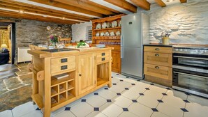 Eine Küche mit Holzausstattung, einem Kühlschrank, einem Backofen und einer Steinwand.