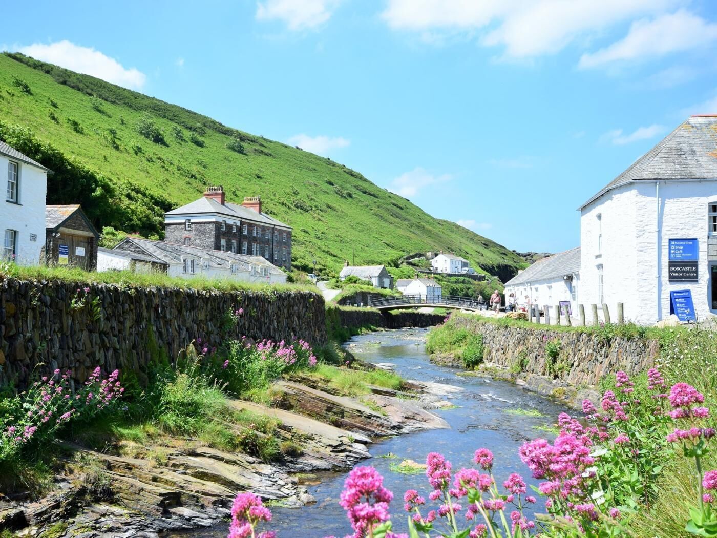 A rural village with stone houses, a river, and a bridge.