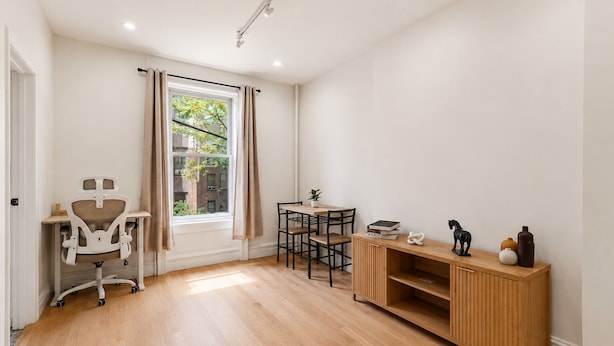 Una habitación con escritorio, silla, mesa de comedor y un armario de madera.