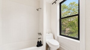 Baño con bañera, inodoro y ventana.