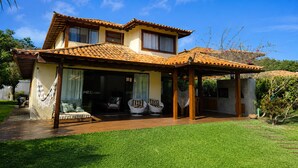 A two-story house with a tiled roof, a covered patio, and a well-maintained lawn. - Villa Serena | Vacation Home for Families and Groups (Armação dos Búzios)