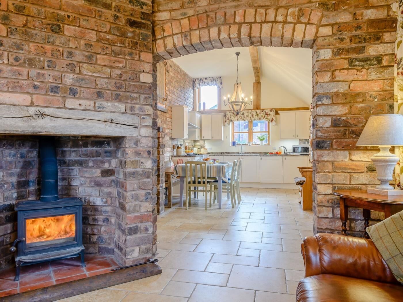 A cozy living room with a fireplace, a dining area, and a kitchen visible through an archway.