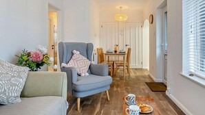 Uma sala de estar com sofá, poltrona e um espaço de jantar com mesa e cadeiras.