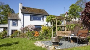 A white house with a garden, a wooden pergola, and outdoor seating. - 2 Bed in Cockermouth (oc-sz381) (Wythop)