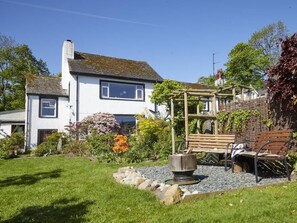 A white house with a garden, a wooden pergola, and outdoor seating. - 2 Bed in Cockermouth (oc-sz381) (Wythop)