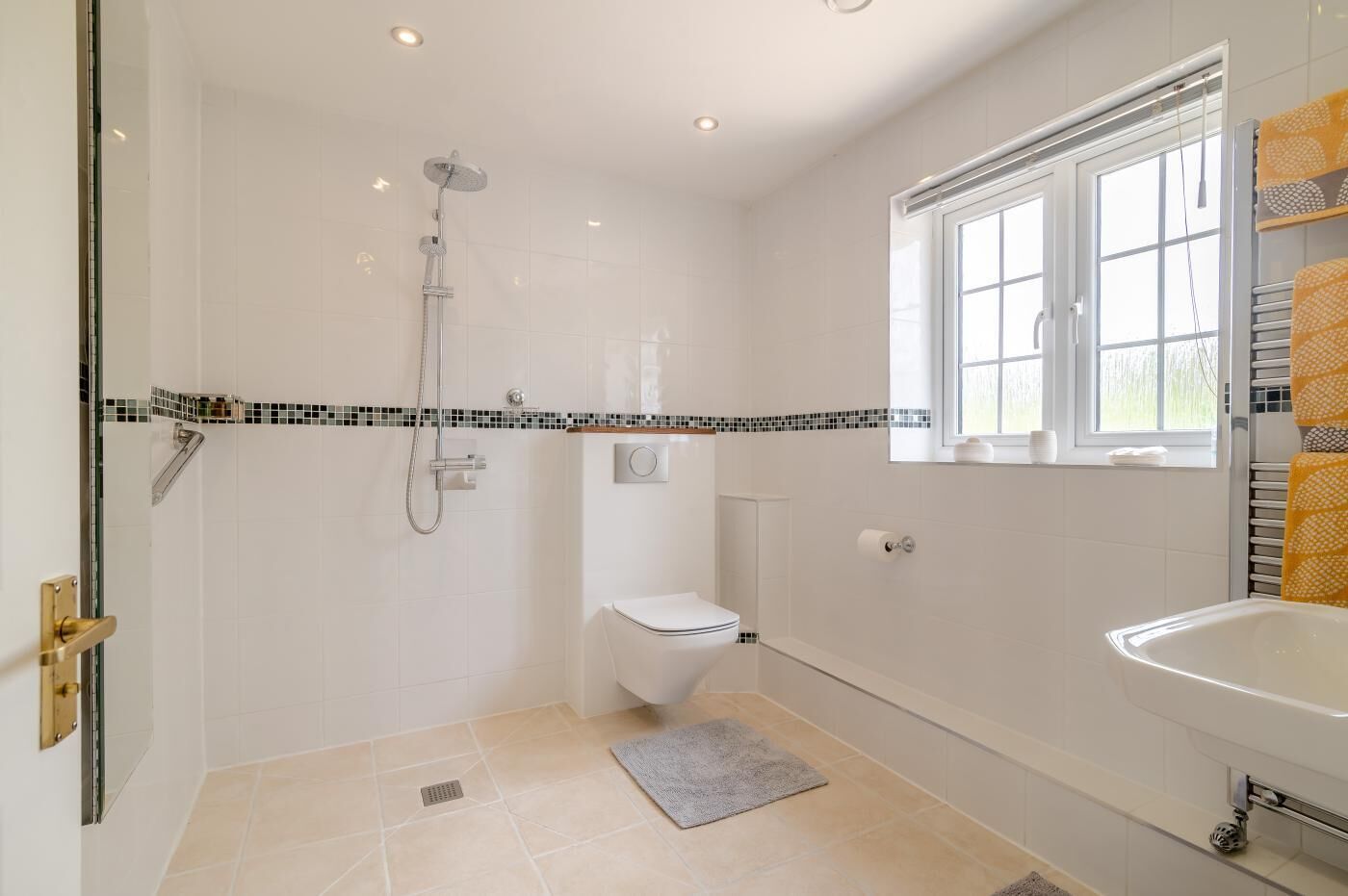 Ein modernes Badezimmer mit Dusche, Toilette und Waschbecken, mit Fliesenboden und Fenster.
