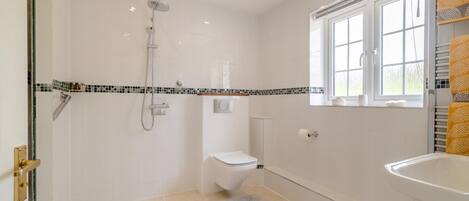 Ein modernes Badezimmer mit Dusche, Toilette und Waschbecken, mit Fliesenboden und Fenster.