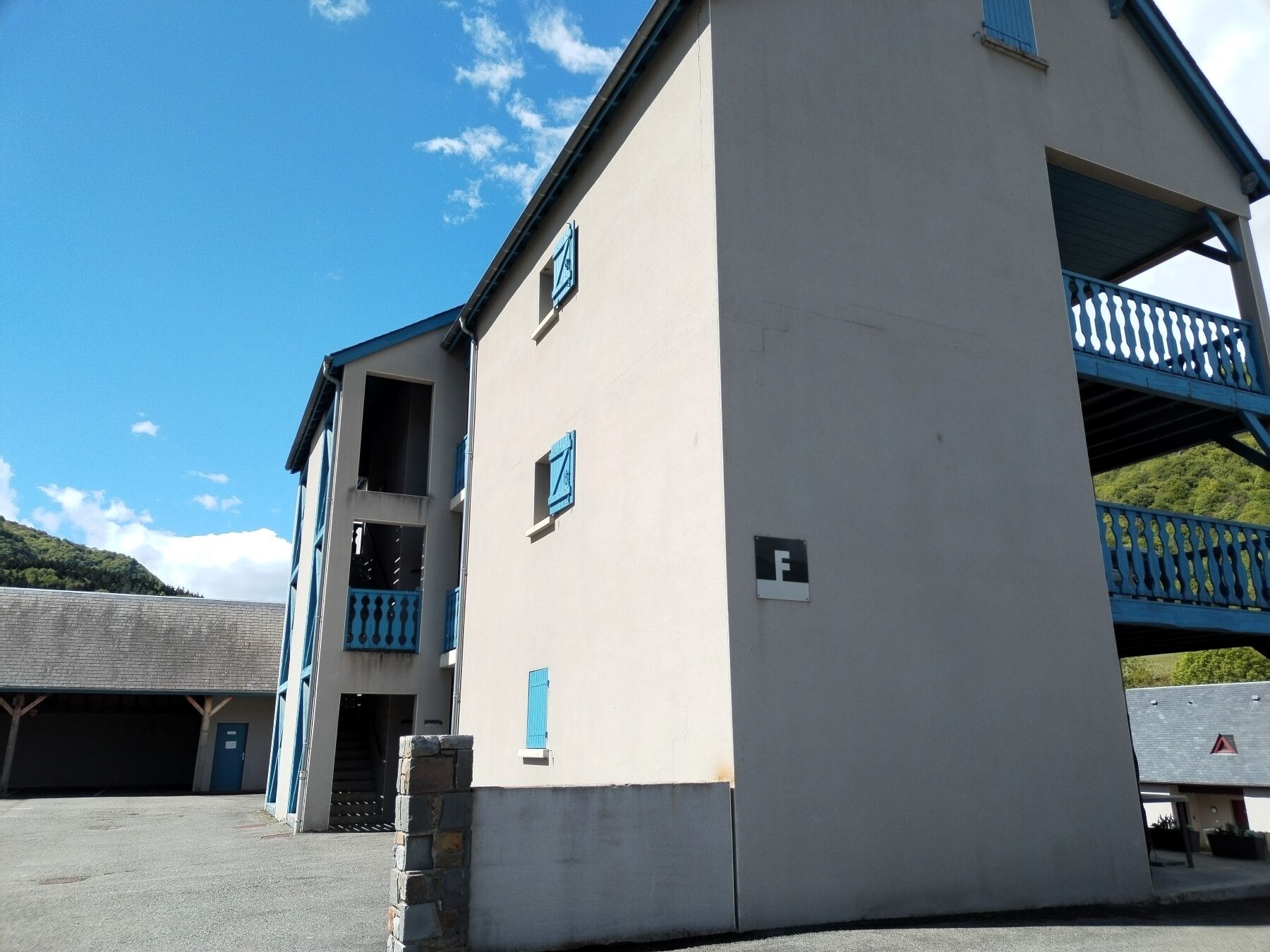 Un edificio con balcón, una puerta y un letrero con la letra 'F'.