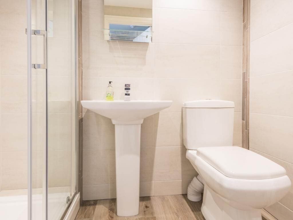 A bathroom with a glass shower enclosure, a pedestal sink, and a toilet.