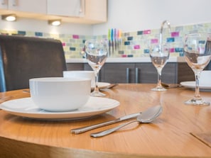A dining table with a white bowl, two wine glasses, and cutlery. - 2 Bed in Keswick (oc-sz215) (Keswick)