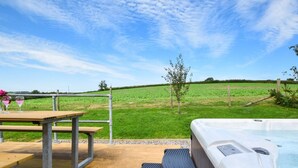 Ein Whirlpool auf einer Holzterrasse mit einem grünen Feld im Hintergrund.