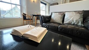 Ein modernes Wohnzimmer mit einer schwarzen Ledersofa, einem Couchtisch und einem Essbereich mit Tisch und Stühlen.