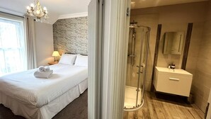 Ein Hotelzimmer mit Bett, Dusche, Schminktisch und einer Chandelier.