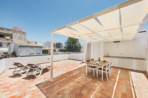 Eine Dachterrasse mit Tisch und Stühlen, einer Pergola und Blick auf die Stadt.