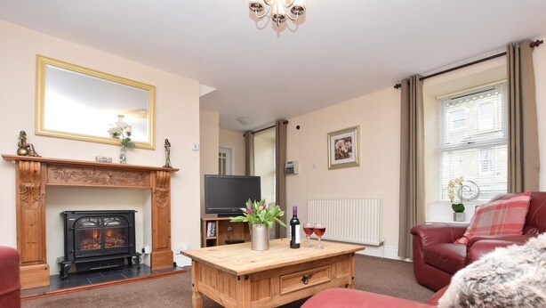 Una sala de estar con chimenea, televisor, mesa de centro de madera y muebles de cuero rojo.