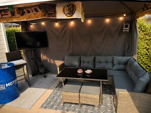 Een terras met een bank, een tafel en een televisie.