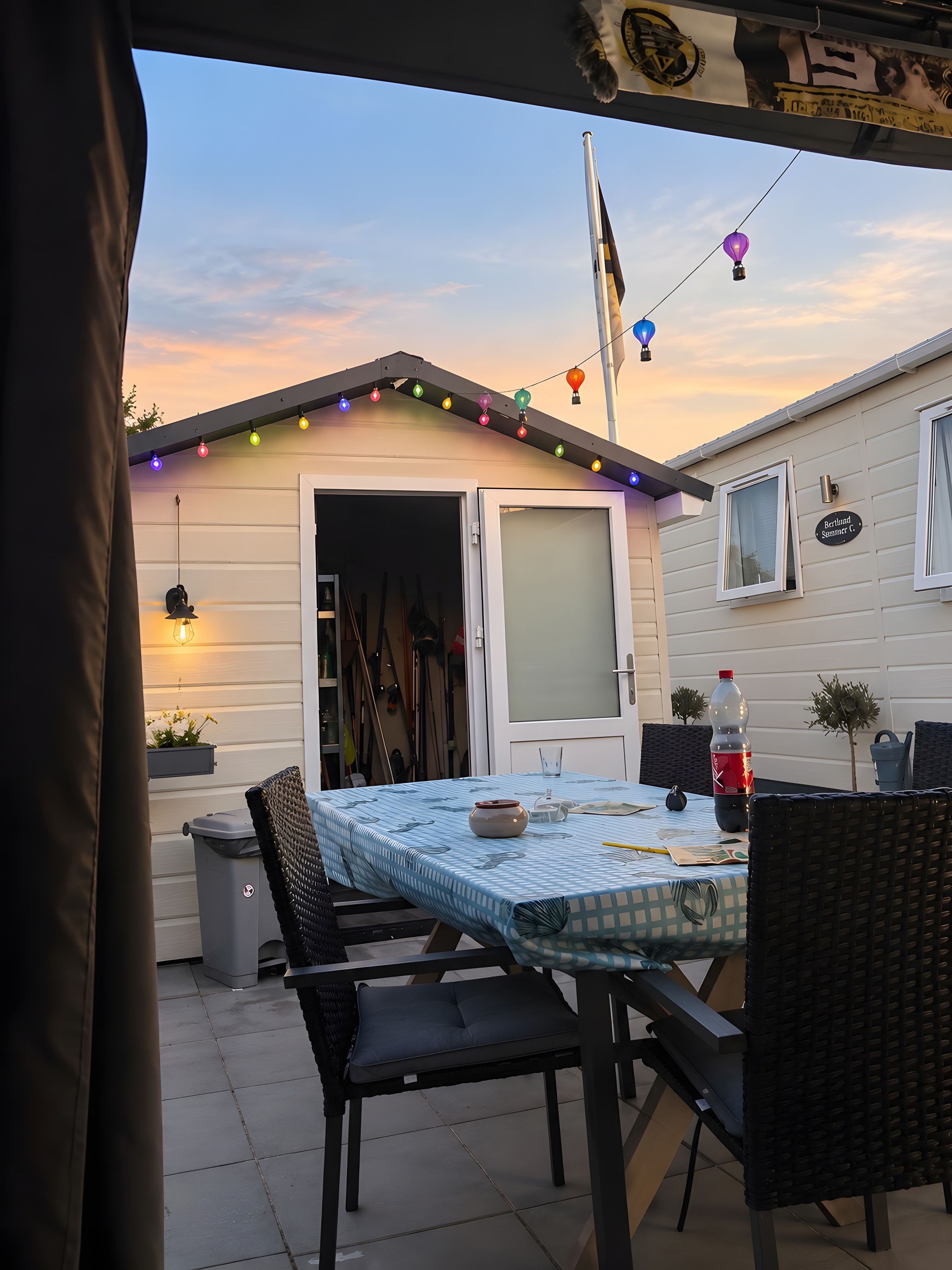 A patio with a table set for dining, outdoor furniture, and a string of colorful lights.