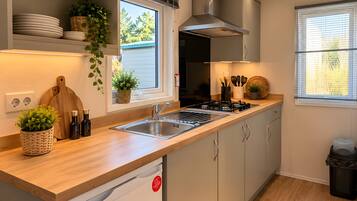 A modern kitchen with a built-in dishwasher, a stove, and a window with blinds.