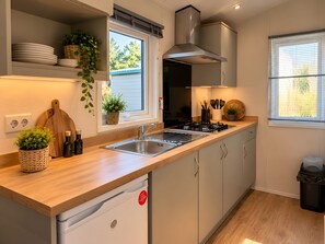 Una cocina moderna con lavavajillas integrado, estufa y ventana con persianas.