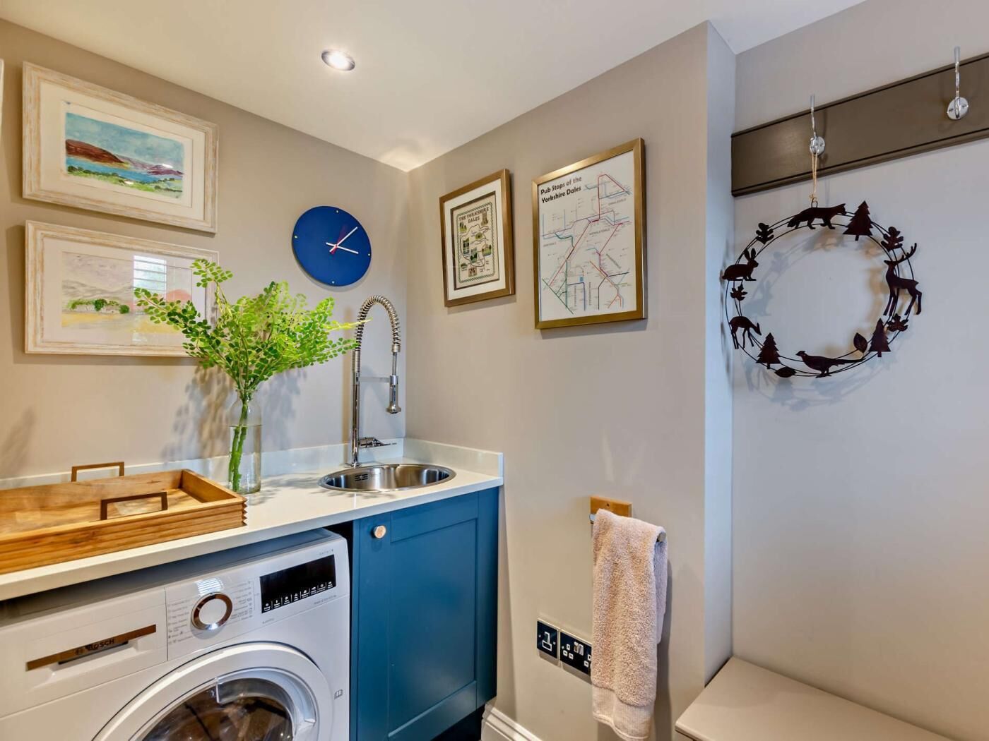 A compact kitchen with a washing machine, a sink, and a clock.