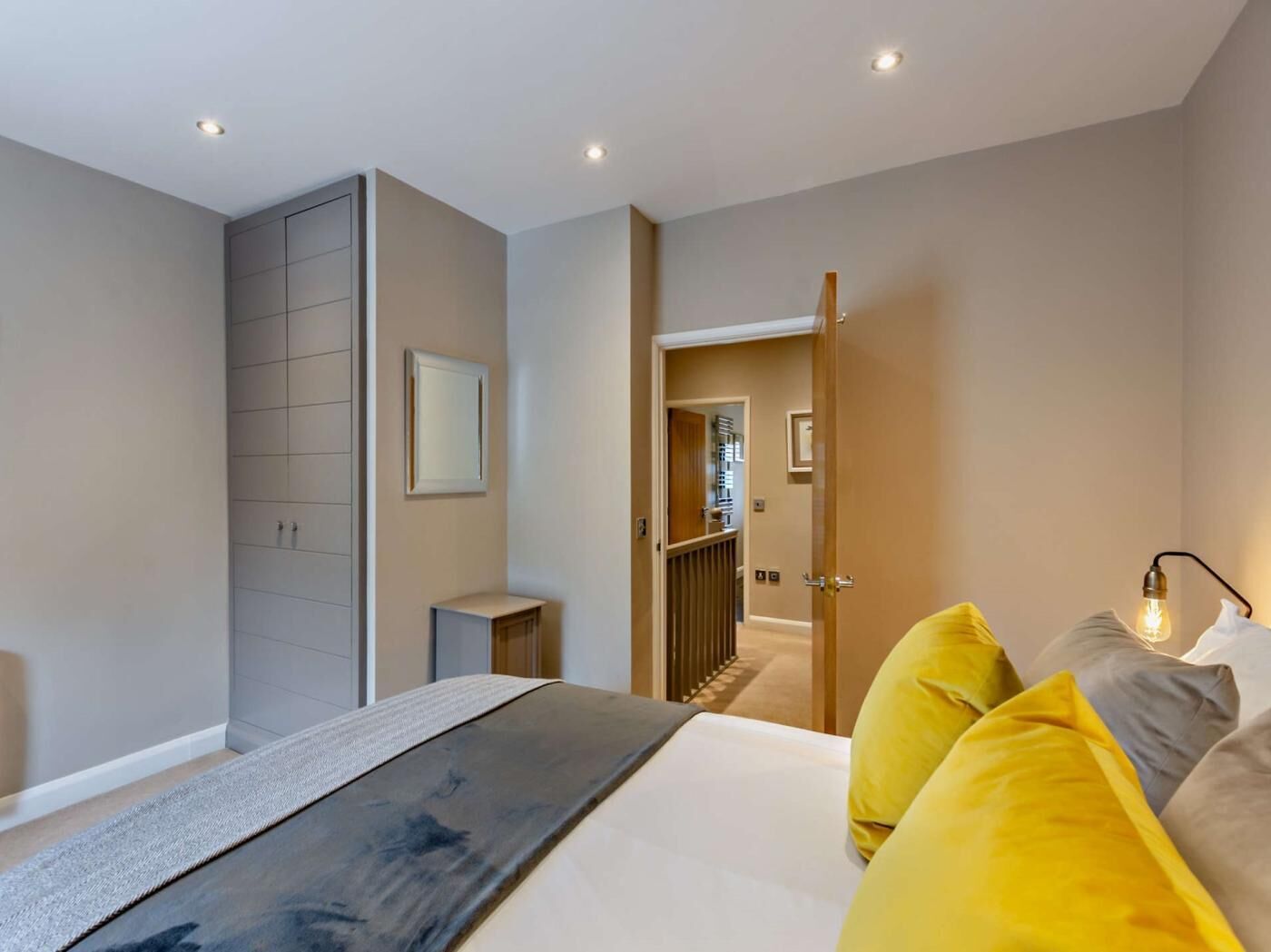 Une chambre à coucher moderne, avec un lit, des lampes de chevet et une vue sur un couloir.