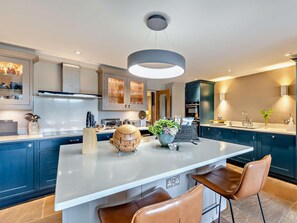 A modern kitchen with a central island, dark blue cabinets, and a pendant light. - 3 Bed in Leyburn (oc-76395) (Askrigg)