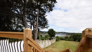 Una escalera de madera que lleva a una terraza con vista a un río y follaje.